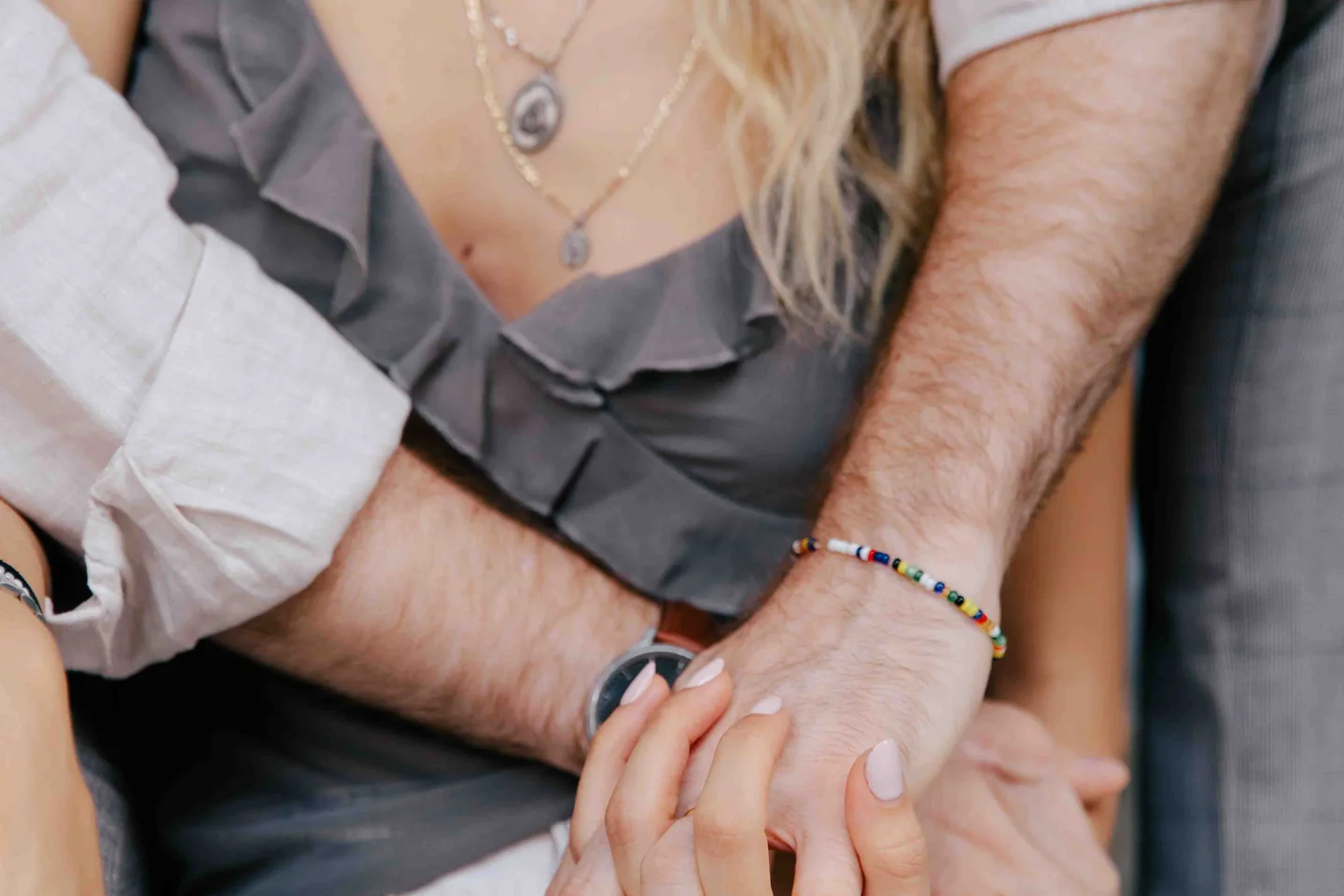 Primer plano de una pareja abrazada: las manos de ella descansan sobre el antebrazo de su pareja